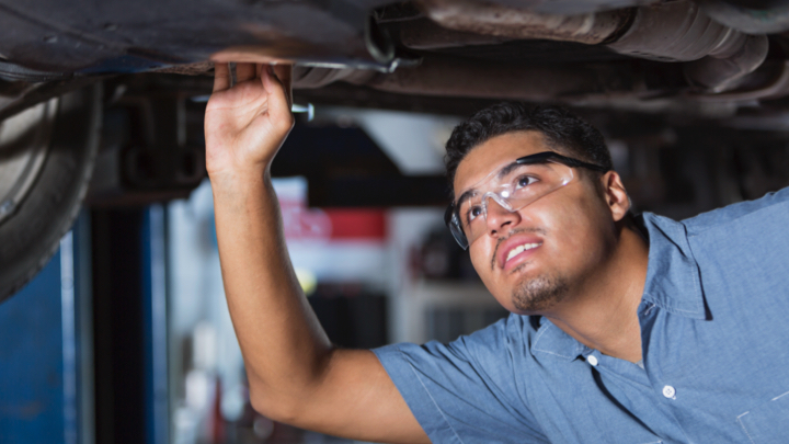 Mechanic inspecting vehicle on car lift with safety glasses on