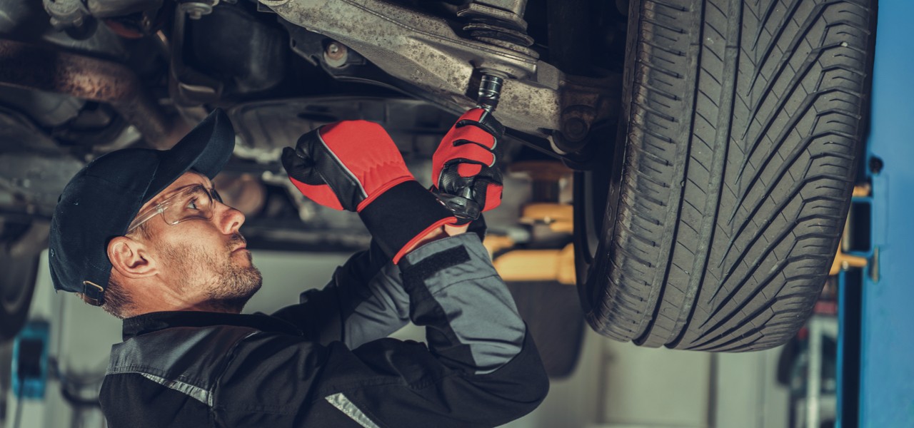 Technician examining vehicle suspension.