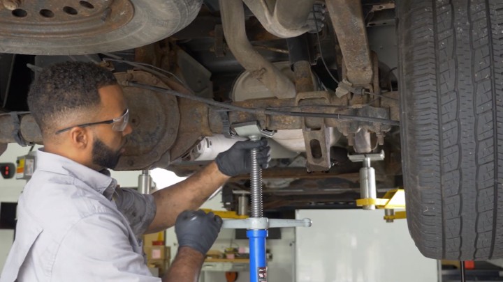 Auto technician supporting vehicle while it's up on a lift