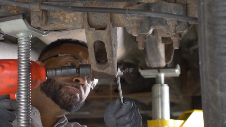 auto-technician-removing-nut-on-vehicle-shock-step-2 Auto technician removing nut on vehicle shock.