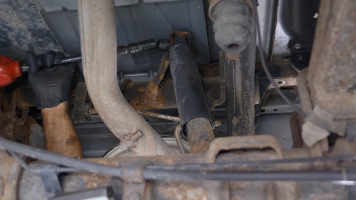 Auto technician removing upper bolt on vehicle shock.