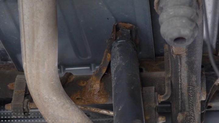 Auto technician removing vehicle shock.