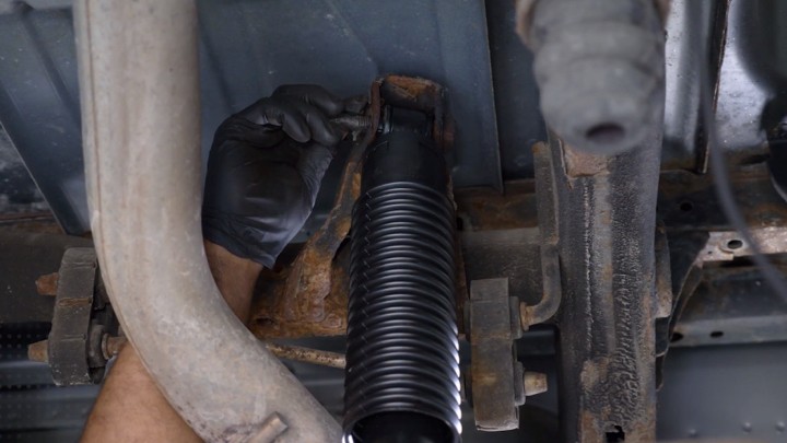 Auto technician positioning new shock on vehicle.