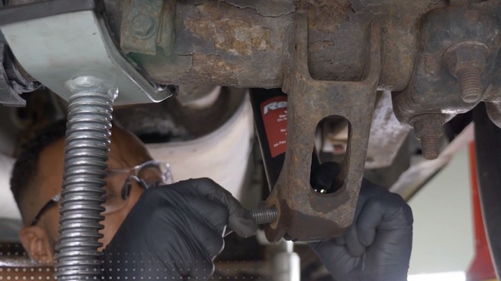 Auto technician loading suspension shock installation.