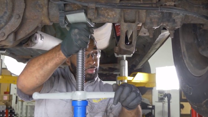 Auto technician lowering vehicle after shock installation.