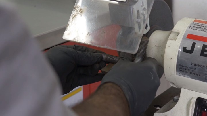 auto-technician-cleaning-bolts-from-shock-step-5 Auto technician cleaning bolts from shock.
