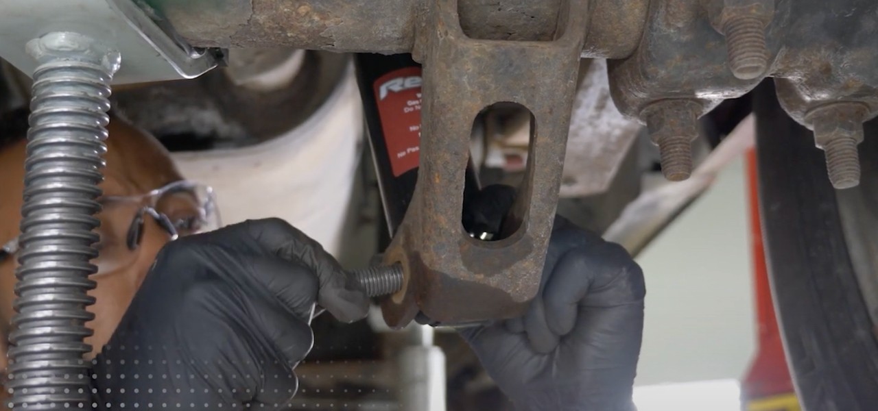 Auto technician installing shock on vehicle.