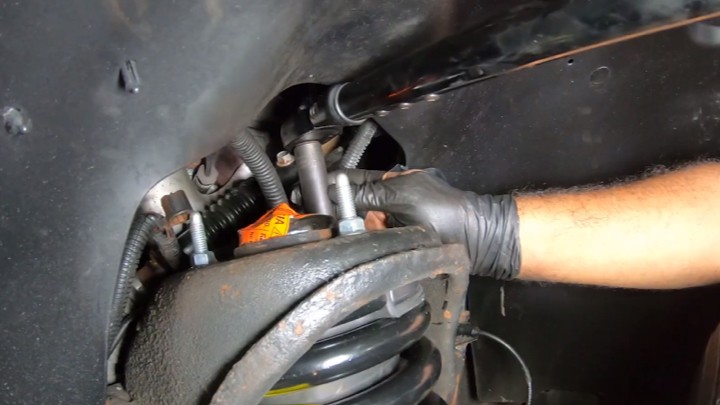 Technician loading the suspension and tightening upper mounting nuts