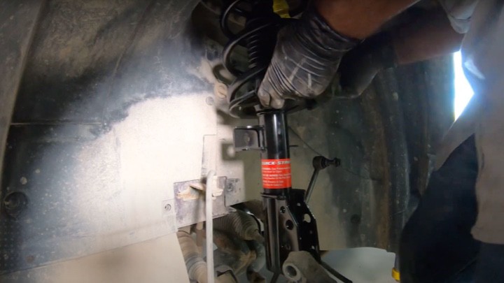 Inserting new strut assembly in vehicle