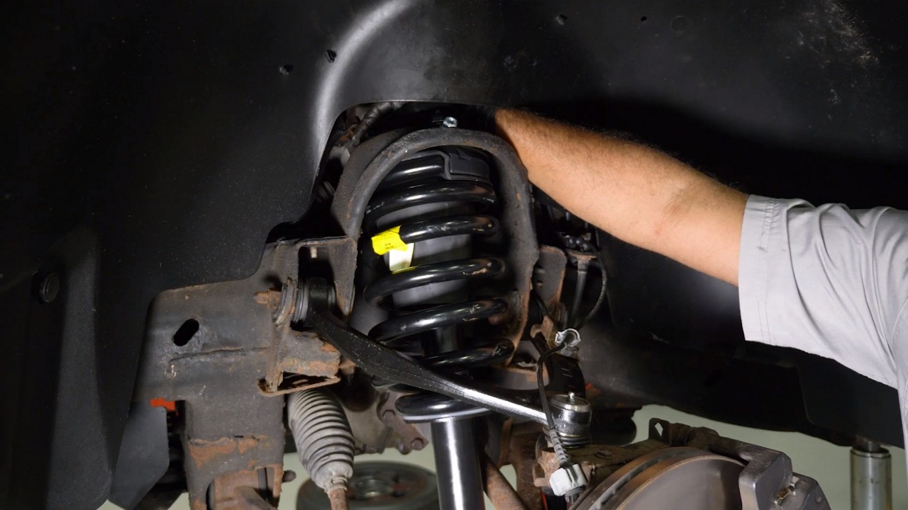 auto-technician-installing-strut-assembly auto-technician-installing-strut-assembly